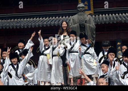 Erste-Klasse tragen traditionelle chinesische Uniformen pose mit einer Statue von Konfuzius und ein Lehrer der Nanjing Konfuzius Tempel Grundschule du Stockfoto