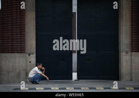 Ein chinesischer Mann raucht vor dem Tor von Tilanqiao Gefängnis in Downtown Shanghai, China, 11. Juli 2013. In der nahen Zukunft, Geschäftsleute in der Innenstadt von Stockfoto