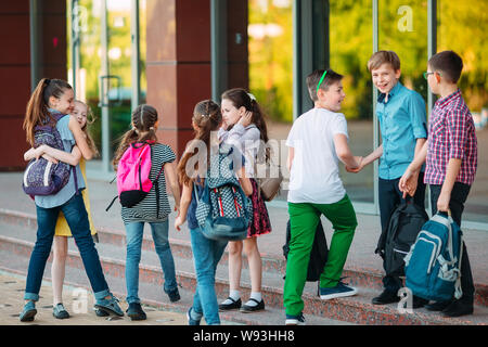 Mitschüler zur Schule gehen. Studenten begrüßen sich. Stockfoto