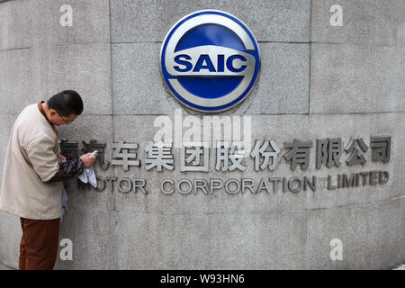 ---- Ein chinesischer Arbeiter Stäube aus dem Logo der SAIC Motor Corporation Limited am Tor der Hauptsitz der SAIC Motor in Shanghai, China, 8 Apri Stockfoto