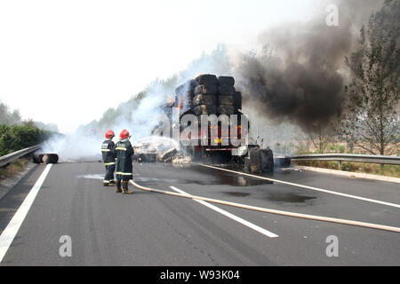 Chinesische Feuerwehrmänner Schlauch Wasser in das Feuer auf ein Fahrzeug mit Baumwolle auf dem Xuchang-Pingdingshan Nanyang Expressway in der Nähe von xuchang Stadt geladen zu löschen, Stockfoto