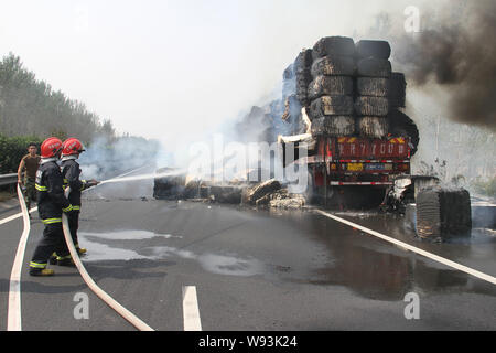 Chinesische Feuerwehrmänner Schlauch Wasser in das Feuer auf ein Fahrzeug mit Baumwolle auf dem Xuchang-Pingdingshan Nanyang Expressway in der Nähe von xuchang Stadt geladen zu löschen, Stockfoto