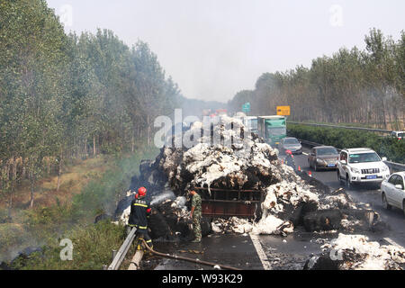 Chinesische Feuerwehrmänner Schlauch Wasser in das Feuer auf ein Fahrzeug mit Baumwolle auf dem Xuchang-Pingdingshan Nanyang Expressway in der Nähe von xuchang Stadt geladen zu löschen, Stockfoto