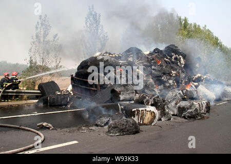 Chinesische Feuerwehrmänner Schlauch Wasser in das Feuer auf ein Fahrzeug mit Baumwolle auf dem Xuchang-Pingdingshan Nanyang Expressway in der Nähe von xuchang Stadt geladen zu löschen, Stockfoto