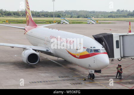 ---- Chinesischen Boden Besatzungsmitglieder sind neben einer Boeing 737-800 Düsenflugzeug von Hainan Airlines am Internationalen Flughafen Sanya Phoenix in S Stockfoto