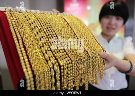 Eine chinesische Angestellte zeigt Gold Halsketten an einem gold Shop in Ganyu County, East China Jiangsu Provinz, 20. Juni 2013. Gold fiel unter $ 1.200 am Freitag (2. Stockfoto