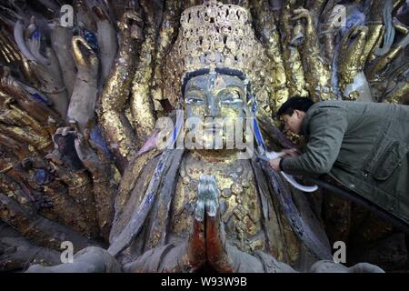 ---- Ein Chinesischer Experte ist die Wiederherstellung der Tausend Hand Bodhisattva, Teil der Posthalterei Felszeichnungen, in Chongqing, China, 4. März 2013. Die steilen h Stockfoto