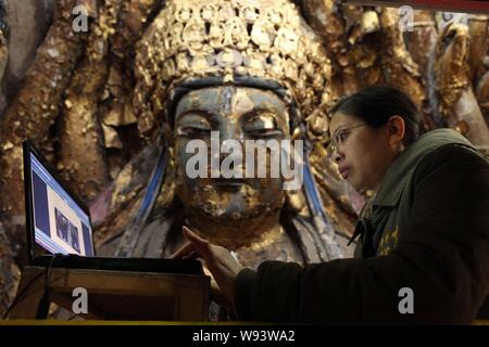 ---- Ein Chinesischer Experte überprüft Ihr Laptop während der Wiederherstellung der Tausend Hand Bodhisattva, Teil der Posthalterei Felszeichnungen, in Chongqing, China, Stockfoto