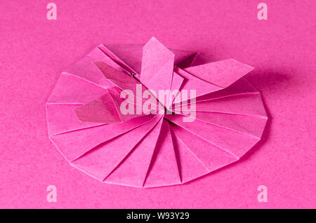Rosa origami Schmetterling und Blüte auf rosa Hintergrund. Japanisches Papier falten Art Flachen quadratischen Blatt Papier in eine fertige Skulptur übertragen. Stockfoto