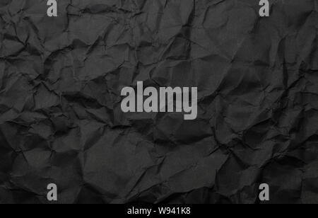 Textur von Schwarzen zerknittertes Papier. Dunkles Papier Hintergrund mit chaotischen Biegungen. Ein Blatt schwarz verknittertes Papier Stockfoto