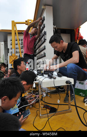 Arbeitnehmer können lokale Bewohner ihre Mobiltelefone, Batterien an einem mobile Ladestation zum Aufladen nach dem 7,0-Erdbeben in Lushan c Stockfoto