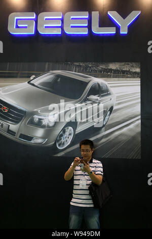 ---- Ein chinesischer Besucher sucht bei seinem Telefon vor dem Stand von Geely während einer Ausstellung in Shanghai, China, 4. Juni 2013. Chinesischen Automobilherstellern Stockfoto