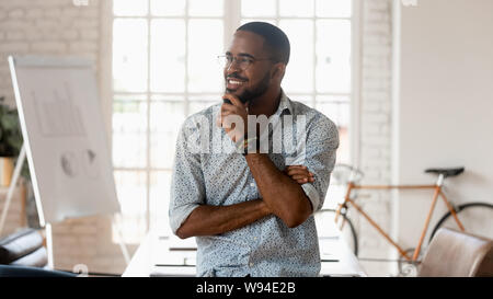 Verträumtes happy African Business Mann denken der Erfolg im Büro Stockfoto