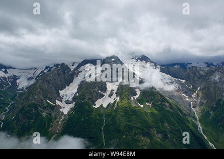 Mountain Green Ridge von Pinien im Nebel und Wolken bedeckt. Dombay, Russland Stockfoto