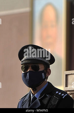 Ein Polizist das Tragen einer Schutzmaske, Wacht vor dem Tiananmen Podiumsplatz in einem Sandsturm in Peking, China, 9. März 2013. Eine Kaltfront bro Stockfoto
