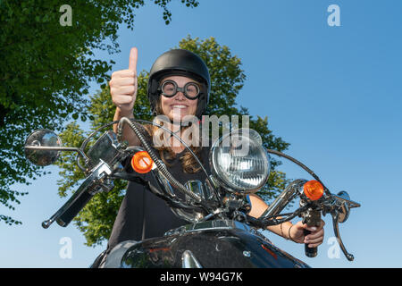 Oung Frau treibt ein Roller und hält den Daumen hoch Stockfoto