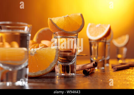 Gläser gold Tequila mit Orange und Zimt Sticks auf einen Tisch in der Bar. Stockfoto