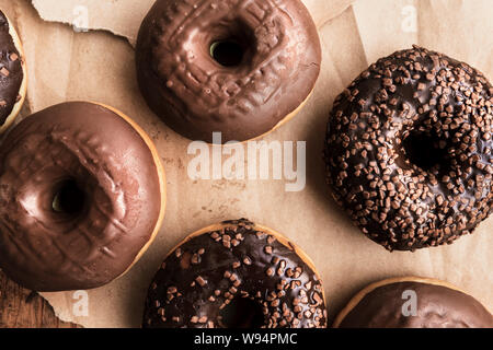 Leckere Schokolade Donuts mit Sahne und Krümel auf rustikalen Holztisch direkt von oben gesehen Stockfoto