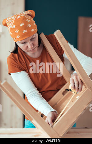 Frau Carpenter Maßband Holz Stuhl Sitz in Small Business Holzarbeiten Workshop, bis der Hände schließen, selektiven Fokus Stockfoto