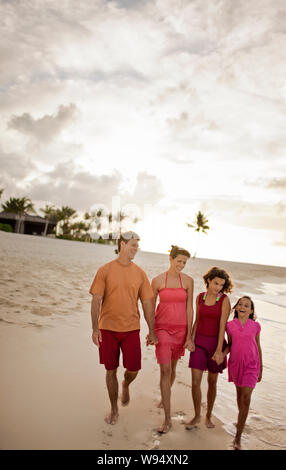 Mitte - erwachsene Paare Hand in Hand mit ihren zwei Töchtern im Teenageralter, da sie zusammen einen Spaziergang am Strand. Stockfoto