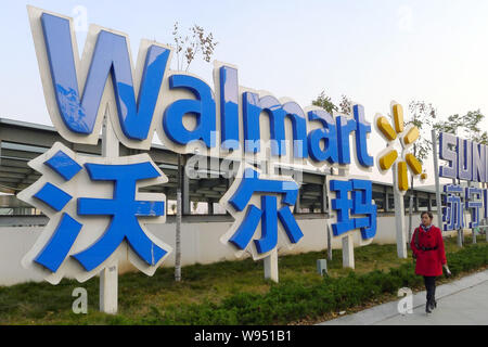 ---- Einen Fußgänger an der Beschilderung von Walmart in Stadt Huaibei, East China Provinz Anhui, 3. Februar 2012. Wal-Mart Stores Inc. s steuerliche f Stockfoto