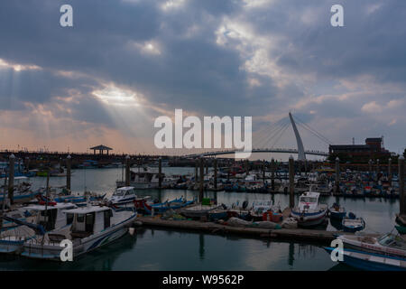 Sonnenstrahlen, Sonnenlicht strömt durch kleine Löcher in die Wolken, Lover's Bridge, kleine Fischerboote, Tamsui Fisherman's Wharf, Taipei, Taiwan Stockfoto