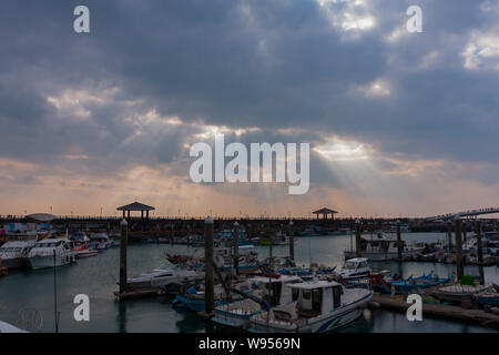 Sonnenstrahlen, Sonnenlicht strömt durch kleine Löcher in die Wolken, kleine Fischerboote, Tamsui Fisherman's Wharf, Taipei, Taiwan Stockfoto