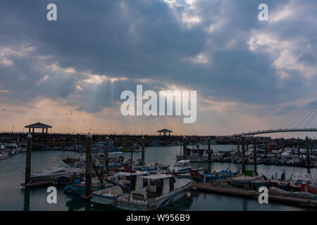 Sonnenstrahlen, Sonnenlicht strömt durch kleine Löcher in die Wolken, kleine Fischerboote, Tamsui Fisherman's Wharf, Taipei, Taiwan Stockfoto