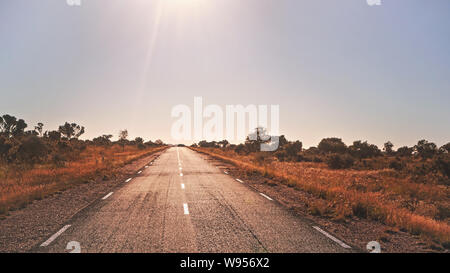 Legendäre RN7 - Steht für Route Nationale - Straße, die durch wilde afrikanische Savanne mit kleinen Bäumen und Sträuchern, in der Region in der Nähe von Ilakaka, Sonne scheint Stockfoto