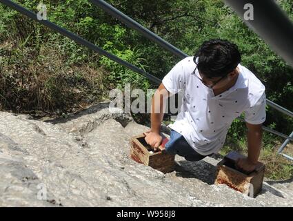 Chinesische beinlose Mann chen Zhou klettert mit seinen Händen die Junji Gipfel des Songshan Berg in Dengfeng zu erreichen, zentrale China Provinz Henan, 12. Juli 2. Stockfoto