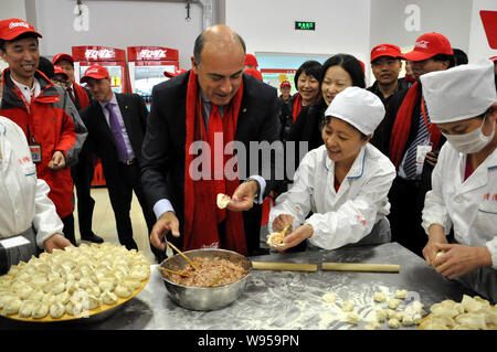 Muhtar Kent, Mitte, Vorsitzender und CEO von The Coca-Cola Company, lernt die Knödel bei der Eröffnung des Coca-Cola Yingkou Werk in Yin Stockfoto