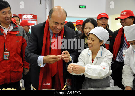 Muhtar Kent, Mitte, Vorsitzender und CEO von The Coca-Cola Company, lernt die Knödel bei der Eröffnung des Coca-Cola Yingkou Werk in Yin Stockfoto