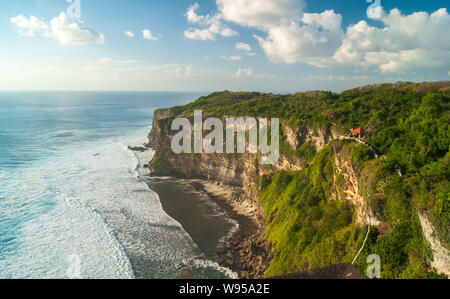 Meer mit Wellen, Felsen und Klippen in Uluwatu, Bali mit blauem Himmel und Wolken Stockfoto