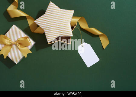 Schwarze Weihnachten Geschenkbox und Preis, Geschenkanhänger auf grünem Hintergrund Stockfoto