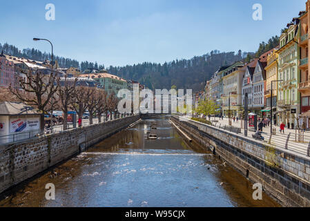 Blick über Fluss Teplá zusammen mit Promenade, Straße und schöne bunte typischen europäischen Gebäuden mit Hintergrund von Berg. Stockfoto