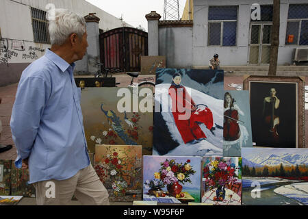 ---- Ein älterer Chinesischer Mann Spaziergänge Vergangenheit Gemälde zum Verkauf an einen Stand auf einer Straße, die während der Fünften Kunst und Kultur Festival der Songzhuang in der S Stockfoto
