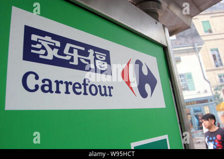 ---- Ein Fußgänger geht hinter einem Schild der Carrefour in Shanghai, China, 30. August 2012. Nach dem Herausziehen aus mehreren Märkten rund um die Welt Stockfoto