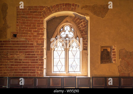 Innen vorne einfache Ansicht im gotischen Stil Fenster mit direkter Sonneneinstrahlung von außen und Wiederherstellung der rauhen gebrochenen alten Mauer, und Zeile Stockfoto