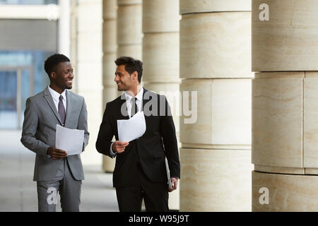 Zwei multiethnischen Manager in formelle Kleidung geschäftliche Verträge und Diskussion von Sitzung beim Gehen im Freien Stockfoto