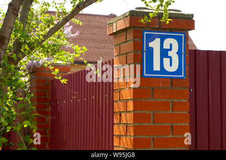 Farbe blau Schild Hausnummer 13 auf einem Red brick wall im Freien. Urban an der Außenseite. Stockfoto
