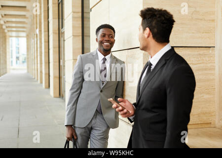 Junge afrikanische Geschäftsmann in Anzug lächelnd zu seinem Kollegen, während sie draußen in der Stadt Stockfoto