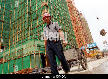 ---- Ein chinesischer Wanderarbeiter zieht eine Karre bei der Baustelle eines von der Regierung finanzierten Residential apartment Projekt in Lianhua Stadt Jiujiang Stockfoto