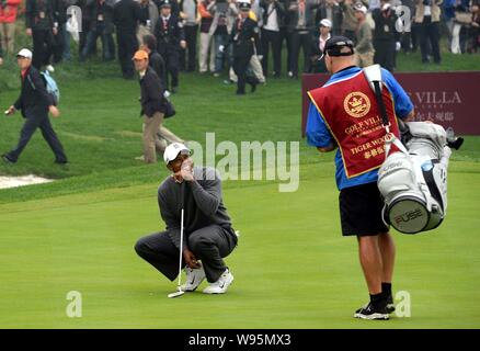 Tiger Woods der Vereinigten erklärte, Links, spricht mit seinem caddie, als er konkurriert gegen Rory McIlroy von Nordirland während der Duell an der Jinsha See Stockfoto