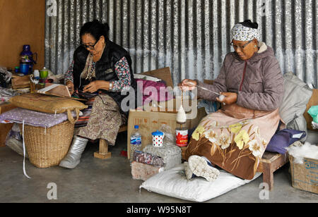 Tibetische Frauen Spinnen von Wolle und Weben an einem Teppich Workshop in Tashi-Ling Tibeter Gemeinschaft in der Nähe von Pokhara, Nepal Stockfoto