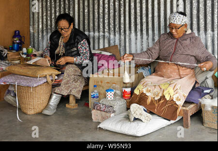 Tibetische Frauen Spinnen von Wolle und Weben an einem Teppich Workshop in Tashi-Ling Tibeter Gemeinschaft in der Nähe von Pokhara, Nepal Stockfoto