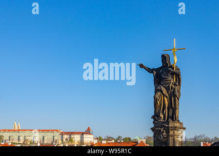 Blick auf die Statue des Heiligen Johannes des Täufers stand auf Sockel und Balustraden der Karlsbrücke über die Moldau und den Hintergrund von Praha Schloss. Stockfoto