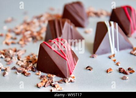 Bunte vegane Schokolade Pralinen und Kakaokerne auf Glas. Stockfoto