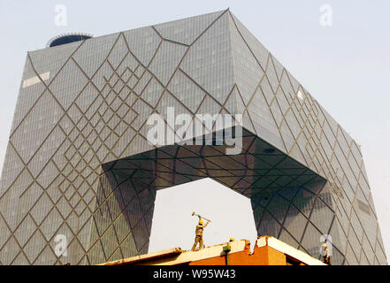 ------ Chinesische Arbeiter ein altes Gebäude vor der neuen CCTV-Tower, die neue Zentrale von China Central Television, in Peking, China, Demolieren, Stockfoto