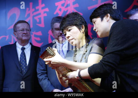 Ehemaligen chinesischen olympischen Tischtennis champion Deng Yaping, zweite rechts, Präsident von Goso. cn, schildern Ihr Autogramm auf eine Fackel während der 2012 Spezielle C Stockfoto