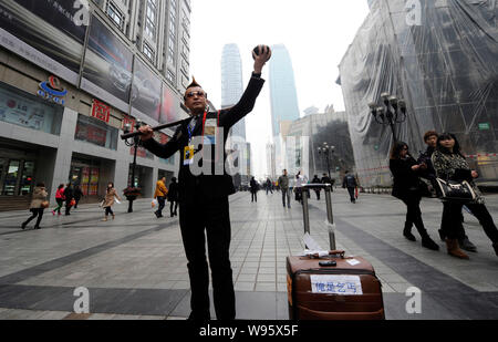 Zhou Fei, wie die Angesagtesten Bettler in China bekannt ist, stellt in einer Fußgängerzone in Chongqing, China, 23. Februar 2012. Anzug, gespritzt Stockfoto